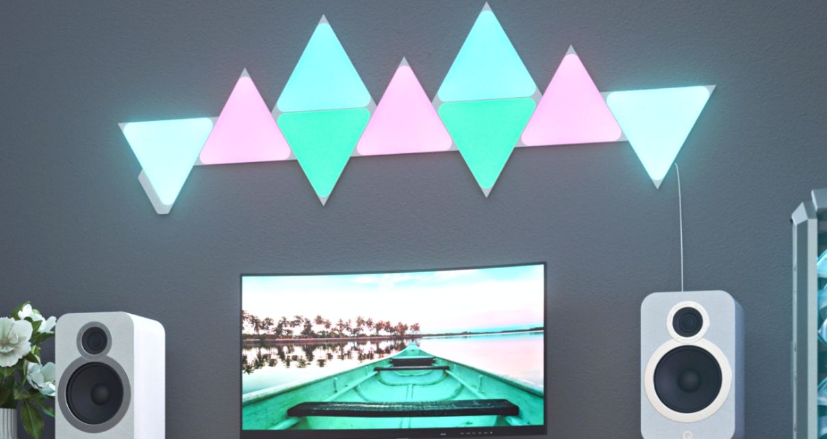 Gray music studio area with desktop, white monitors, and tropical blue and blue Nanoleaf lights attached to the wall. 